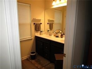 2210 Palm Court, Sandston, VA 23150 Bathroom featuring a dual-sink vanity with dark cabinetry, light-toned countertop, large wall-mounted mirror, and overhead light fixture