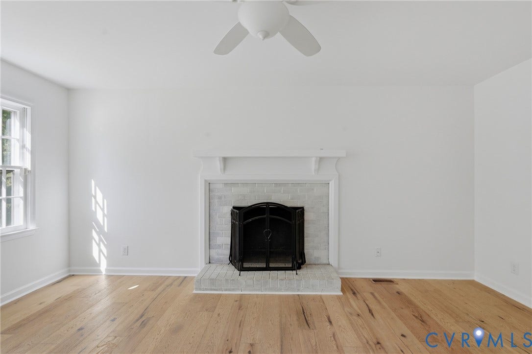 12506 Mandolin Drive, Chesterfield, VA 23113 Fireplace featuring a light-toned brick surround, raised hearth, and mantel, complemented by wood-finish flooring and a ceiling-mounted fan