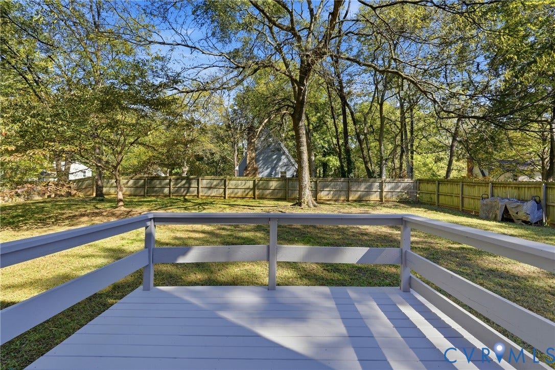12506 Mandolin Drive, Chesterfield, VA 23113 Raised wooden deck featuring a painted finish and horizontal railing, overlooking a level backyard with mature trees and perimeter wood fencing