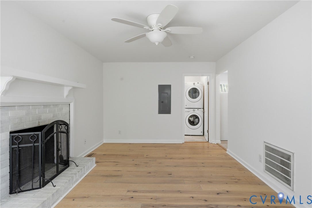12506 Mandolin Drive, Chesterfield, VA 23113 Fireplace with a painted brick surround and mantel, wood-finish flooring, ceiling fan, and built-in stacked laundry appliances