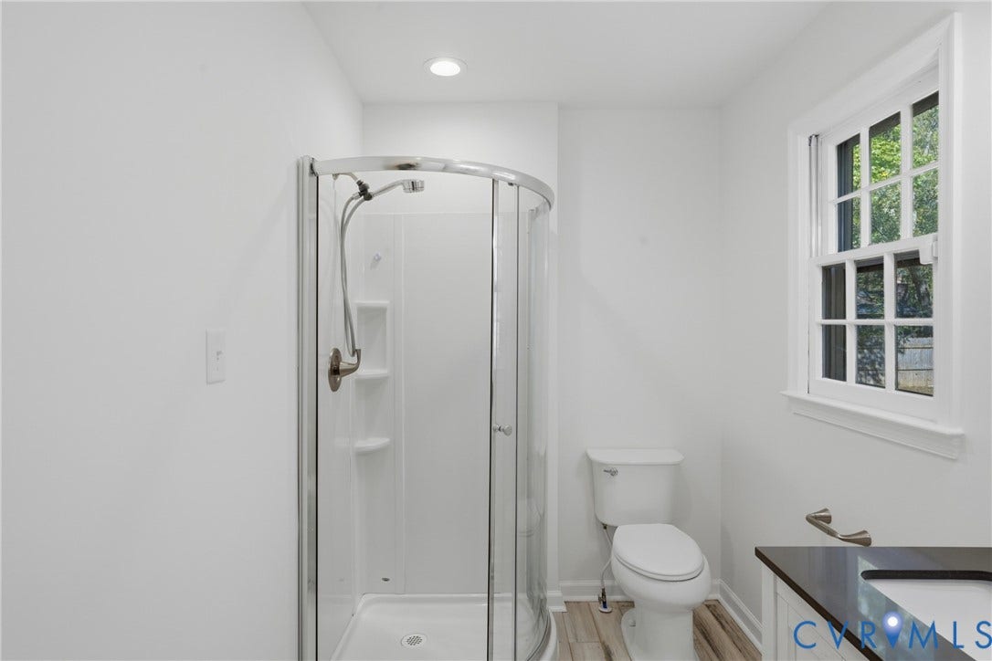 12506 Mandolin Drive, Chesterfield, VA 23113 Bathroom featuring a glass-enclosed corner shower, white porcelain toilet, vanity with a dark solid-surface countertop, recessed ceiling lighting, and wood-finish flooring