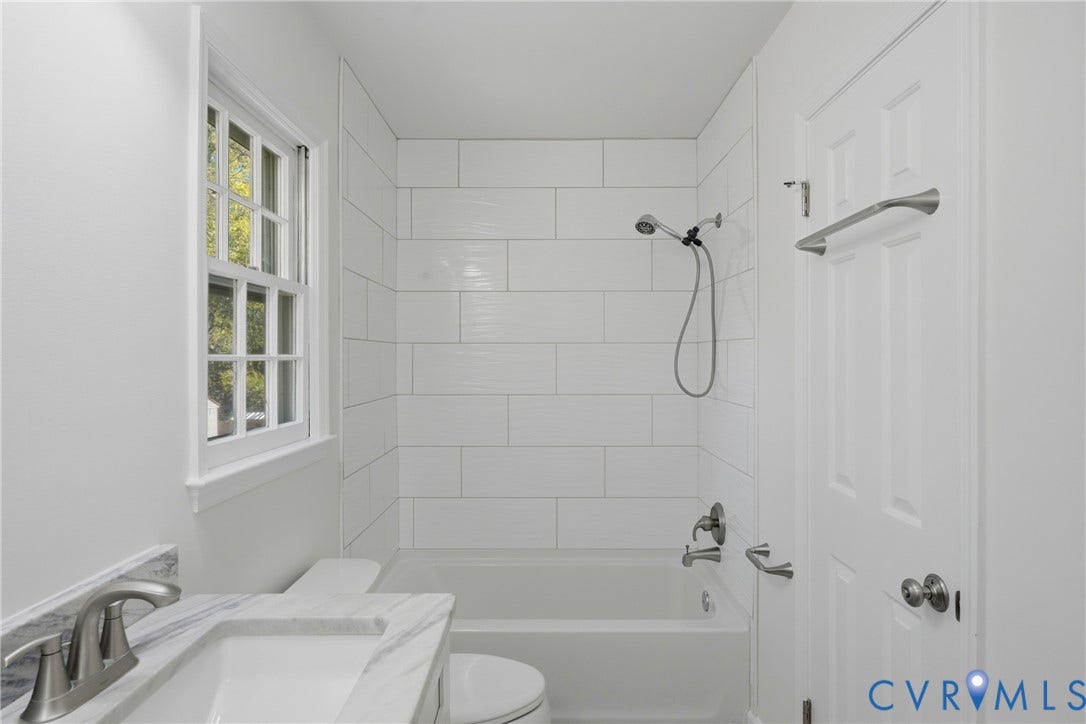 12506 Mandolin Drive, Chesterfield, VA 23113 Bathroom featuring a stone-top vanity with an undermount sink, subway tile shower surround, window, and brushed nickel hardware