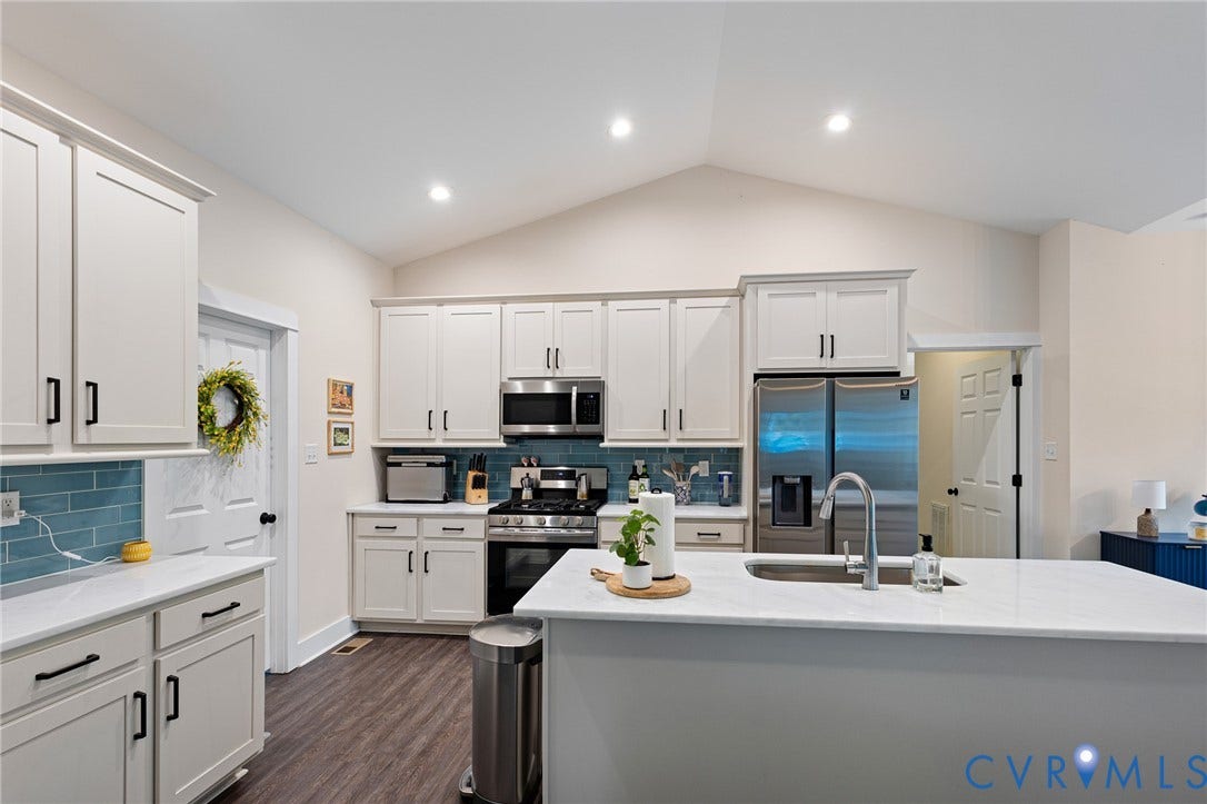 360 Anderson Mill Drive, Anderson Mill, Bumpass, VA 23024 Kitchen featuring white cabinetry, quartz countertops, a central island with a stainless steel sink, tiled backsplash, and vaulted ceilings
