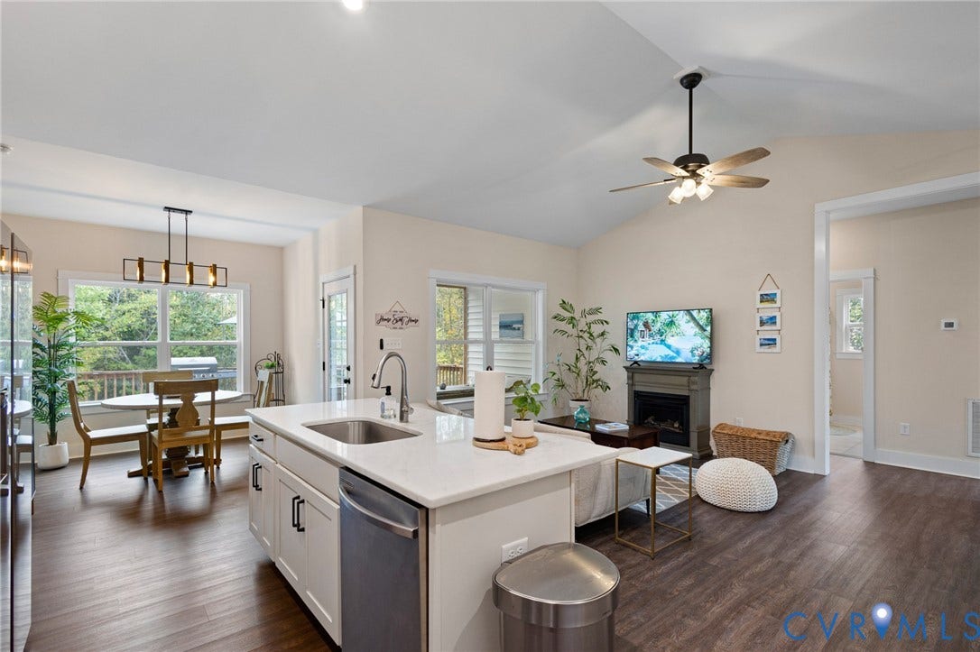 360 Anderson Mill Drive, Anderson Mill, Bumpass, VA 23024 Open-concept interior featuring vaulted ceilings, wood-finish flooring, a central kitchen island with stone-surface countertops, and a built-in fireplace