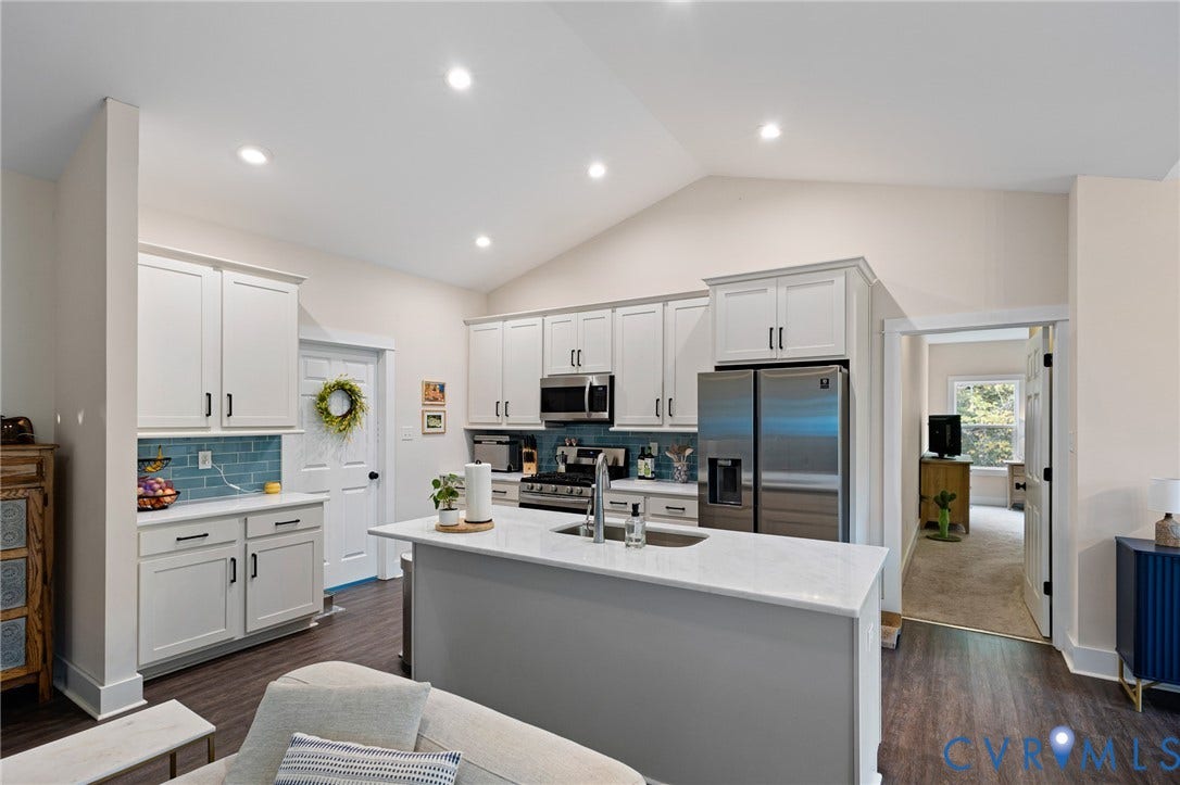 360 Anderson Mill Drive, Anderson Mill, Bumpass, VA 23024 Kitchen featuring a central island with stone-surface countertop, white cabinetry, blue tiled backsplash, stainless steel appliances, and wood-finish flooring under a vaulted ceiling