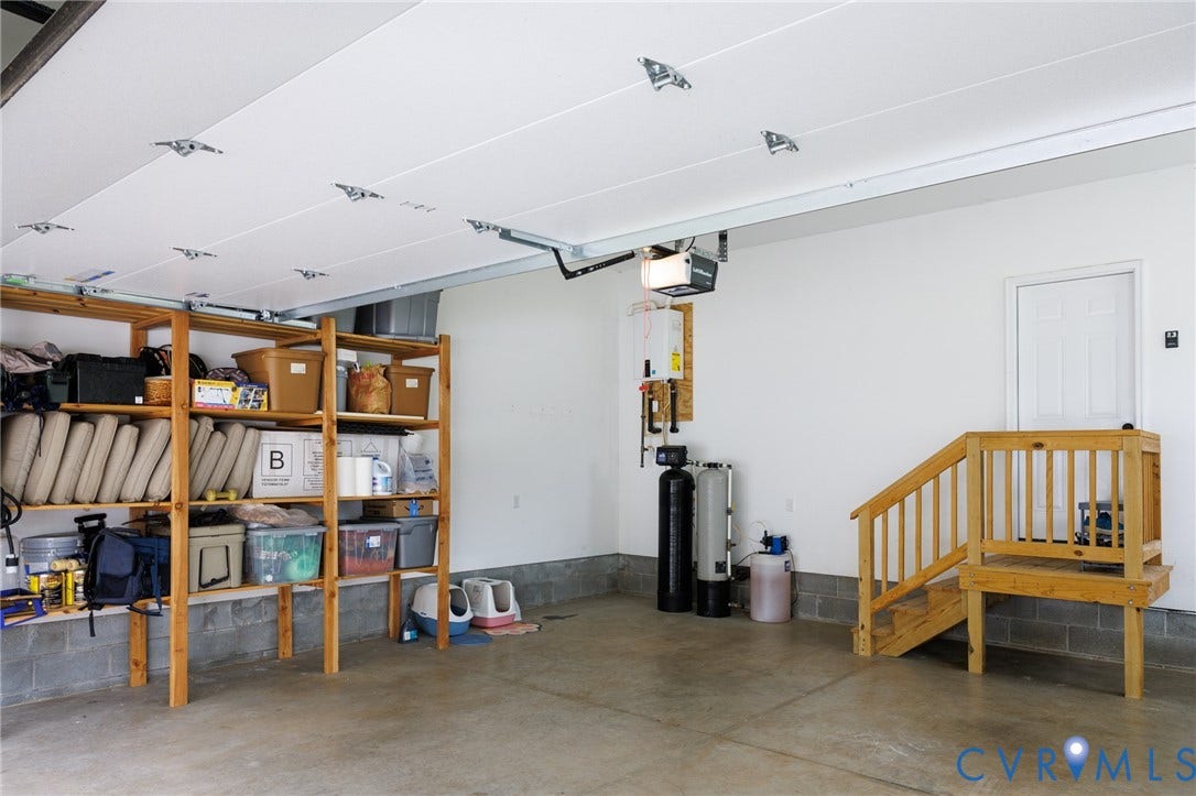 360 Anderson Mill Drive, Anderson Mill, Bumpass, VA 23024 Finished garage space featuring smooth walls, concrete flooring, water treatment system, and wooden staircase with railing