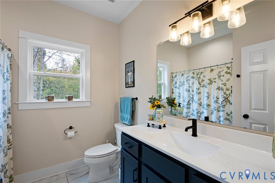360 Anderson Mill Drive, Anderson Mill, Bumpass, VA 23024 Bathroom featuring a vanity with dark cabinetry and a white countertop, an integrated basin, a matte black faucet, and a large-format vanity mirror with integrated four-bulb lighting