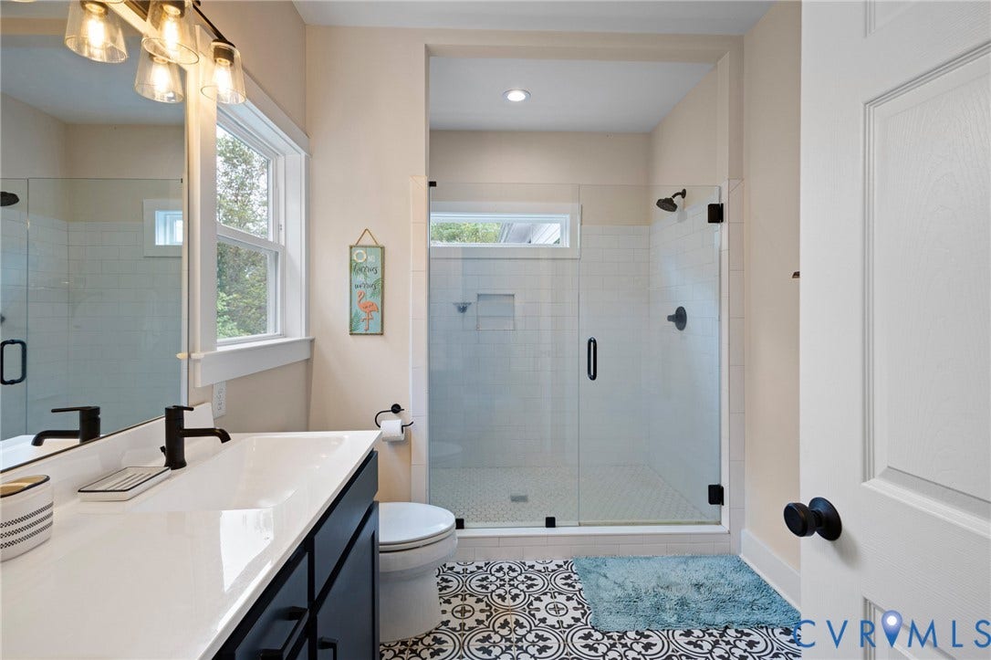 360 Anderson Mill Drive, Anderson Mill, Bumpass, VA 23024 Bathroom featuring a dark vanity with a white countertop, patterned tile flooring, a glass-enclosed shower with subway tile surround, and matte black hardware