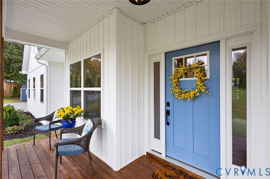 360 Anderson Mill Drive, Anderson Mill, Bumpass, VA 23024 Covered front porch with wood-finish decking, vertical board siding, blue entry door with a window insert, and sidelight windows
