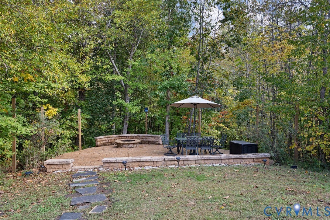 360 Anderson Mill Drive, Anderson Mill, Bumpass, VA 23024 Flagstone pathway leading to a paved patio featuring a built-in stone fire pit and tiered retaining walls