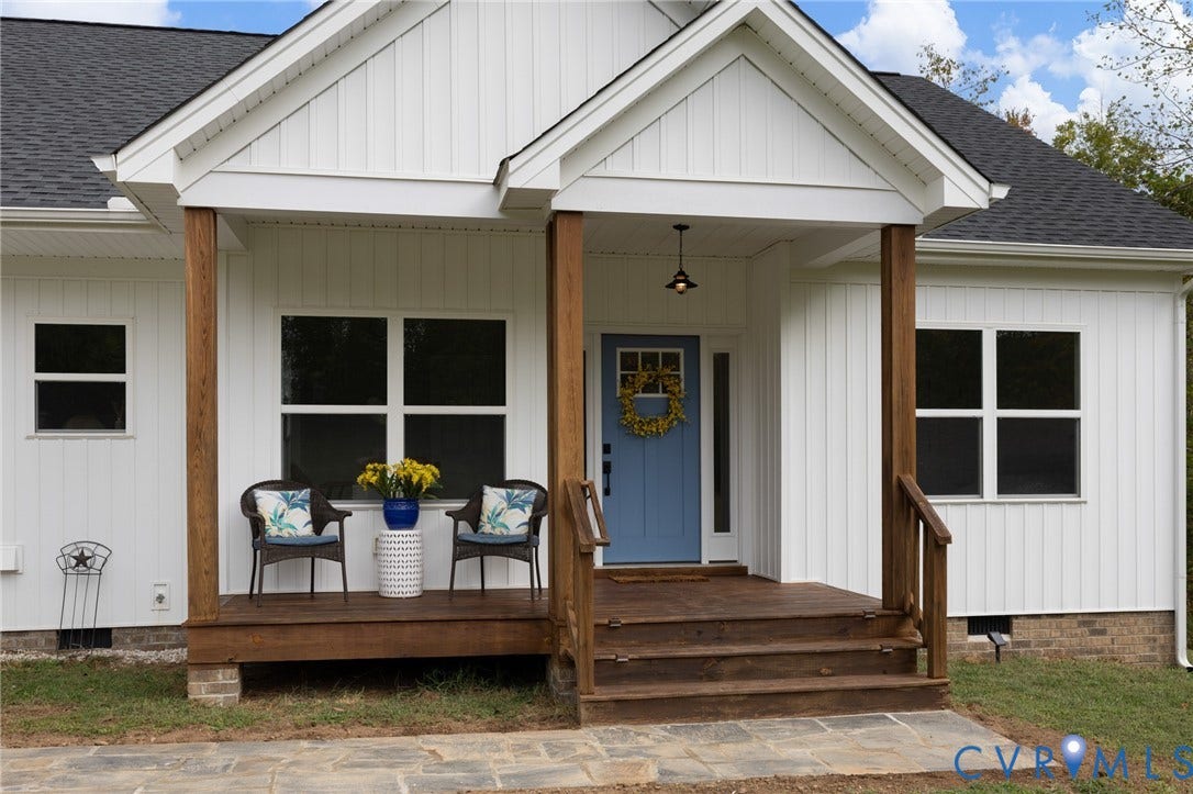360 Anderson Mill Drive, Anderson Mill, Bumpass, VA 23024 White board-and-batten siding exterior featuring a covered front porch with wood-finish decking, natural timber support posts, and a stone-paver walkway