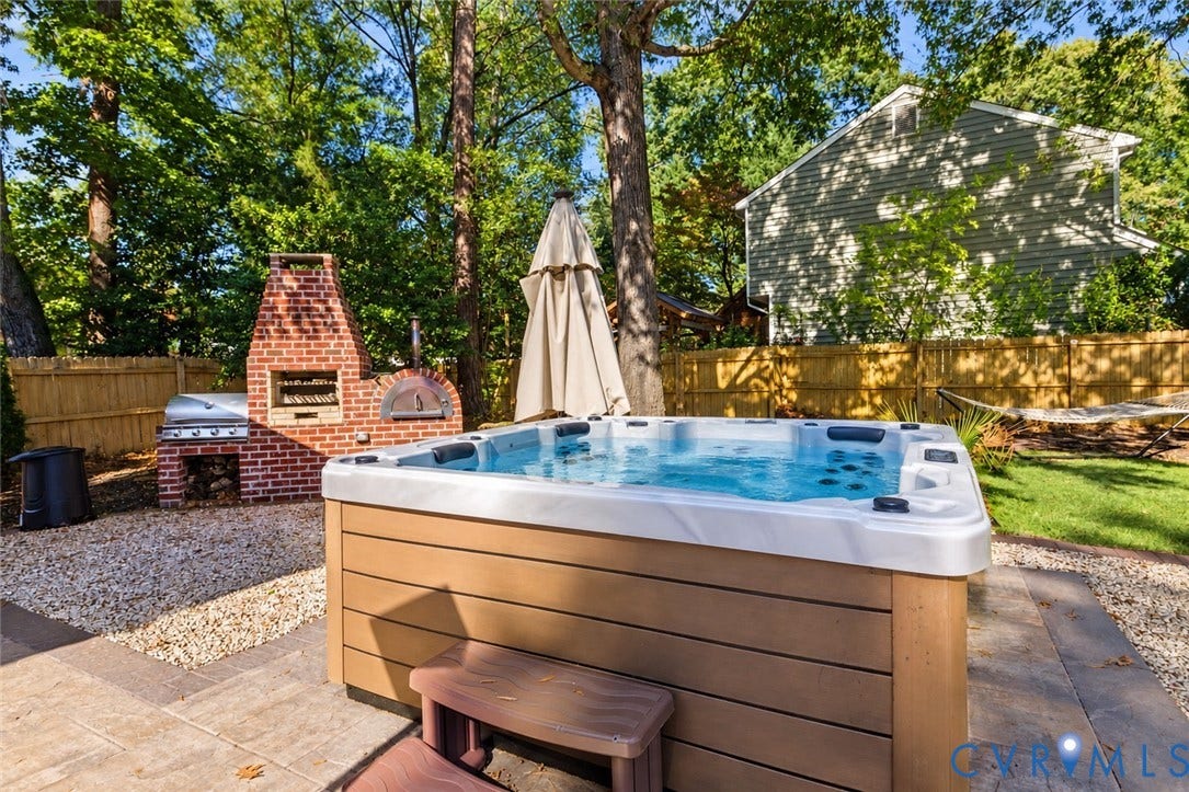 4504 Argonne Court, Glen Allen, VA 23060 *digitally enhanced to remove spa cover* Outdoor living space featuring a built-in red brick wood-fired oven and grill, integrated hot tub, and fenced backyard area