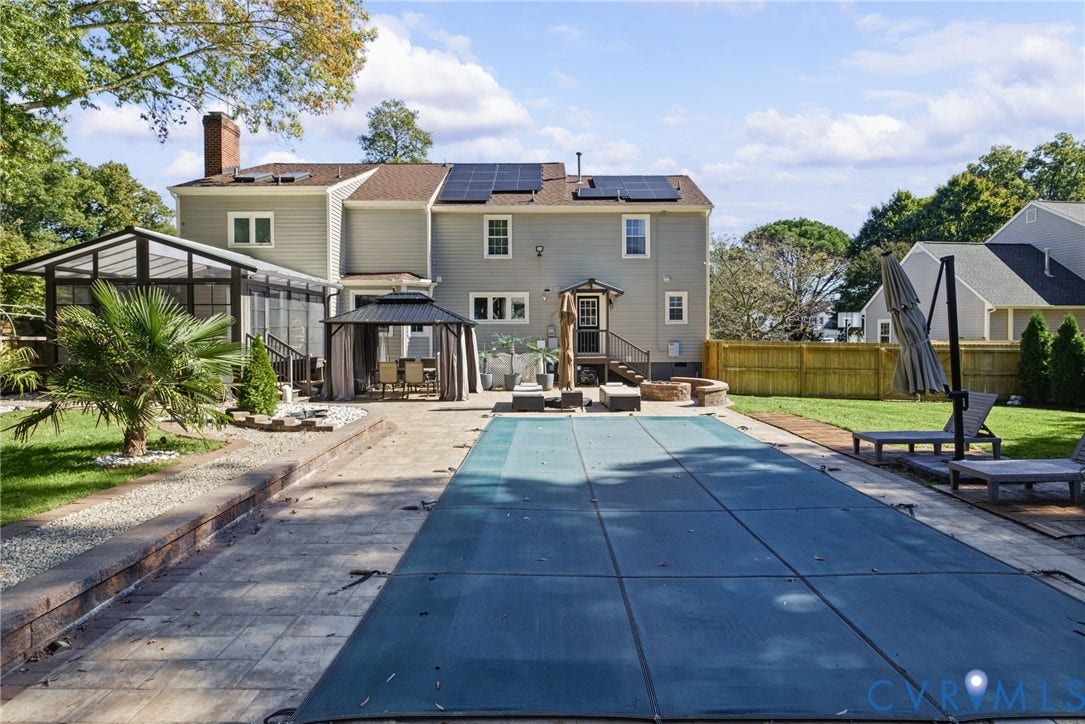 4504 Argonne Court, Glen Allen, VA 23060 Exterior view featuring a backyard in-ground pool with safety cover, stone paver patio, attached sunroom, integrated solar panels, and wood fencing