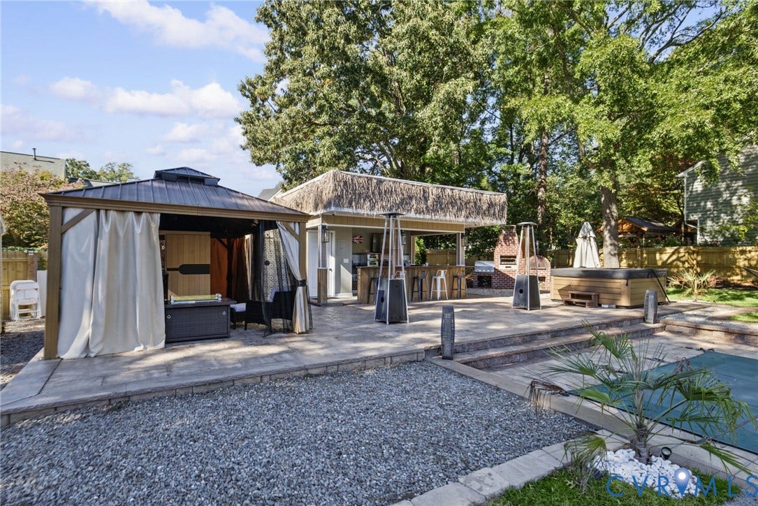 4504 Argonne Court, Glen Allen, VA 23060 Multi-level paver patio featuring a covered gazebo, a built-in outdoor kitchen with bar seating, an integrated brick fireplace, and a concrete-surround pool