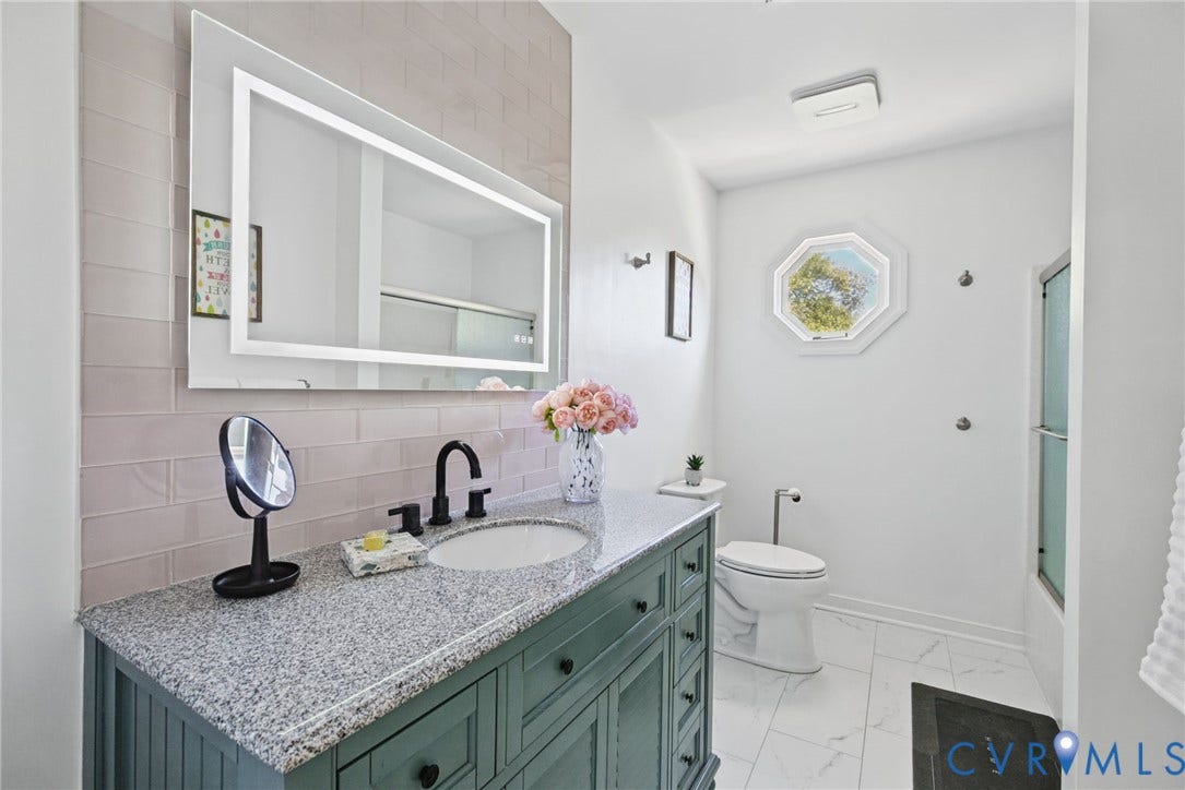 4504 Argonne Court, Glen Allen, VA 23060 Bathroom featuring a vanity with stone-finish countertop, undermount sink, and matte black faucet, illuminated LED mirror, herringbone-patterned tile backsplash, and octagonal window