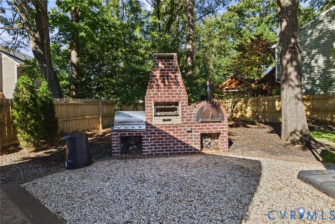 4504 Argonne Court, Glen Allen, VA 23060 Outdoor masonry structure featuring a brick fireplace, built-in stainless steel grill, integrated pizza oven, and dual wood storage niches set upon a stone-surfaced patio