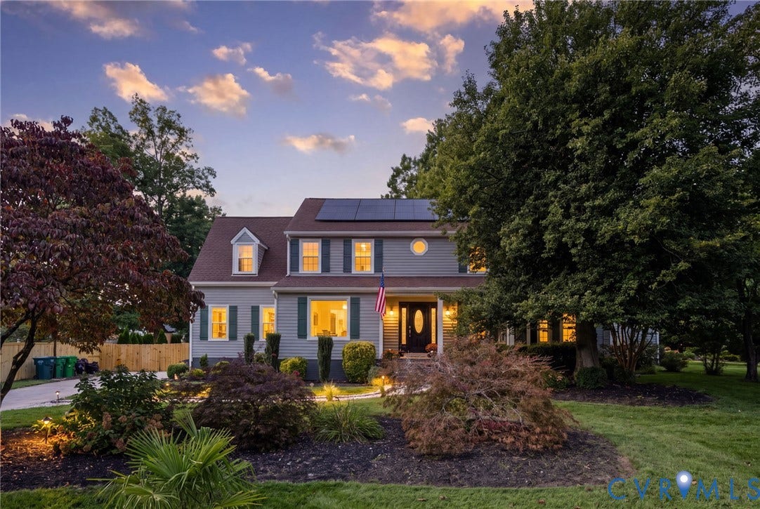 4504 Argonne Court, Glen Allen, VA 23060 * Digitally altered to simulate twilight* Two-story residence featuring grey lap siding, rooftop solar panels, dark-toned shutters, a prominent roof dormer, and a covered front entryway with a decorative glass-panel door