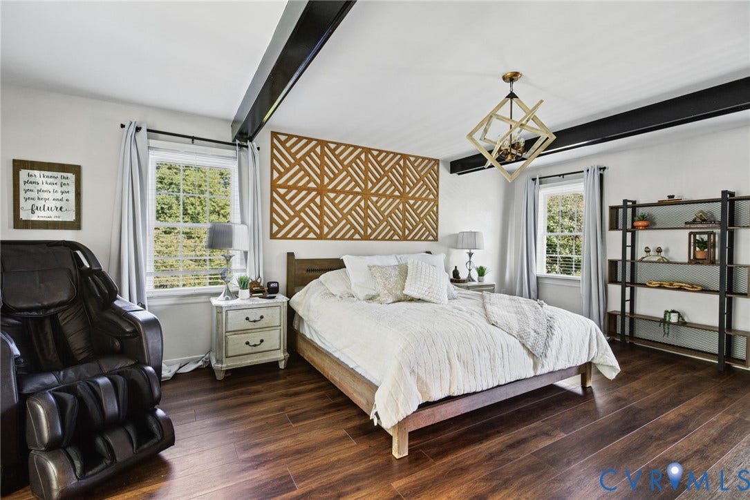 4504 Argonne Court, Glen Allen, VA 23060 Bedroom featuring wood-finish flooring, exposed black ceiling beams, geometric wall accent paneling, and a metallic geometric pendant light fixture