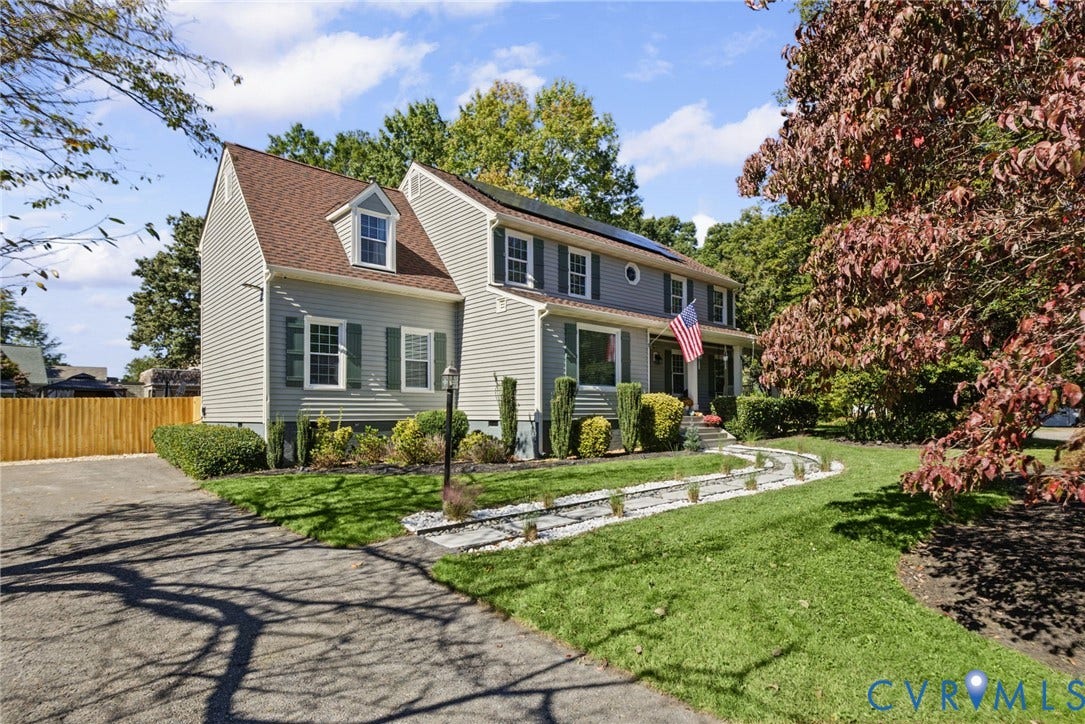 4504 Argonne Court, Glen Allen, VA 23060 Two-story residence featuring light gray siding, a shingled roof with integrated solar panels, a stone-lined walkway, and landscaped garden beds