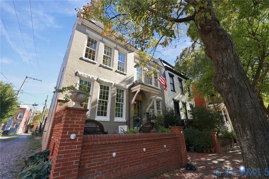 107 N Harvie Street, The Fan, Richmond, VA 23220 Three-story brick exterior featuring a prominent red brick perimeter wall, multi-pane windows, a covered entryway with decorative bracket supports, and a brick-paved front landing