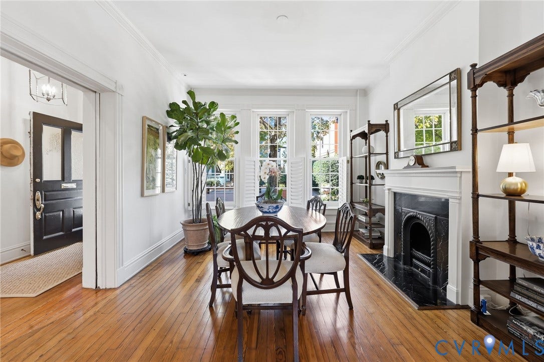 107 N Harvie Street, The Fan, Richmond, VA 23220 Hardwood flooring, triple-window configuration with plantation shutters, decorative fireplace featuring a black stone surround and a carved mantel, crown molding, and a dark-finished solid wood entry door with glass pane detail