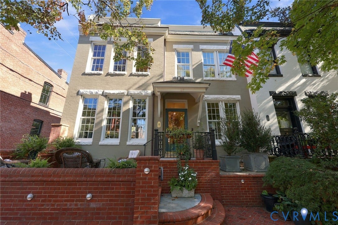 107 N Harvie Street, The Fan, Richmond, VA 23220 Painted brick exterior featuring a covered entryway, multi-pane windows with stone-style lintels, and a low-profile red brick retaining wall with integrated lighting