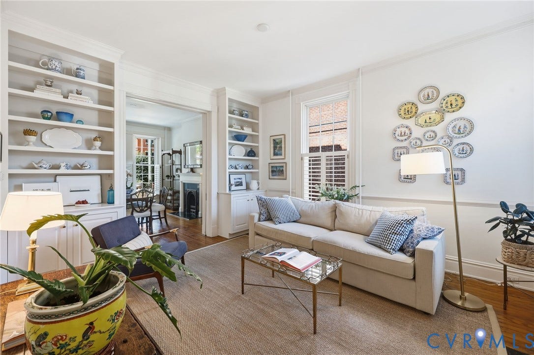 107 N Harvie Street, The Fan, Richmond, VA 23220 Living area featuring tall built-in bookshelves, chair rail molding, wood-finish flooring, and multi-pane windows with interior shutters