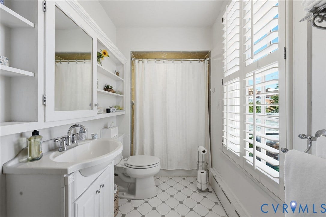 107 N Harvie Street, The Fan, Richmond, VA 23220 Bathroom featuring a pedestal-style vanity with integrated sink, built-in recessed shelving, plantation shutters, and geometric patterned floor tile
