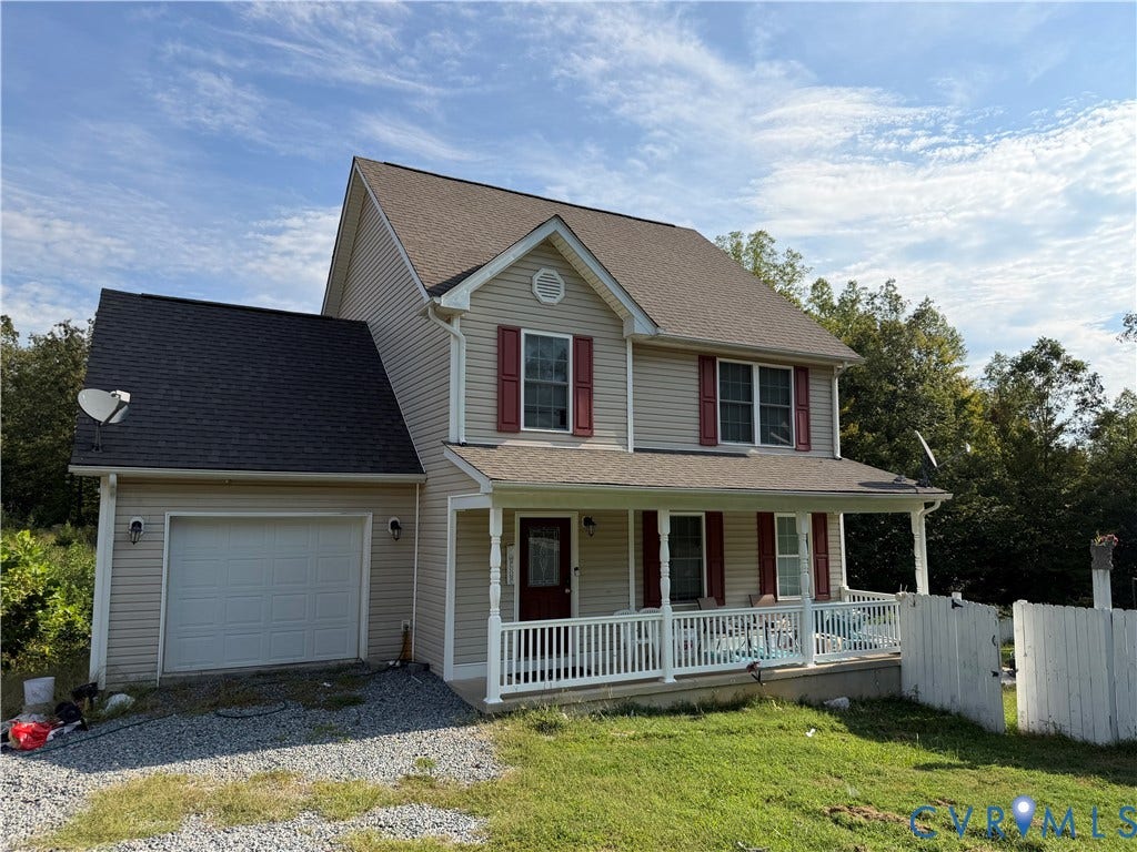 227 Boulder Springs Lane, Louisa, VA 23093 Two-story residence featuring light-toned horizontal siding, contrasting shutters, a front-facing covered porch with white railing, a pitched roof, and an attached garage