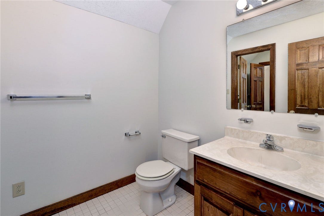 14151 Black Horse Lane, Lanexa, VA 23089 Bathroom featuring a wood-finish vanity with a stone-composite countertop, integrated sink, wall-mounted mirror, and tile flooring
