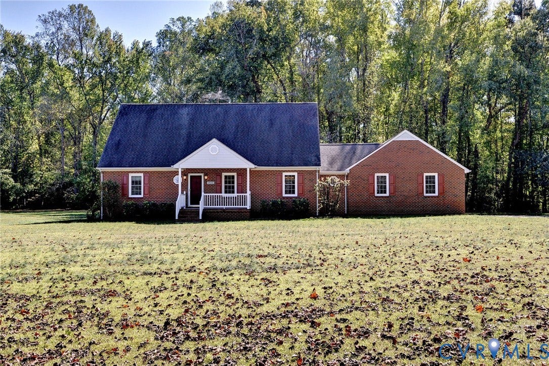 14151 Black Horse Lane, Lanexa, VA 23089 Traditional brick exterior featuring a covered front porch, gabled roofline, decorative window shutters, and expansive grounds surrounded by mature trees