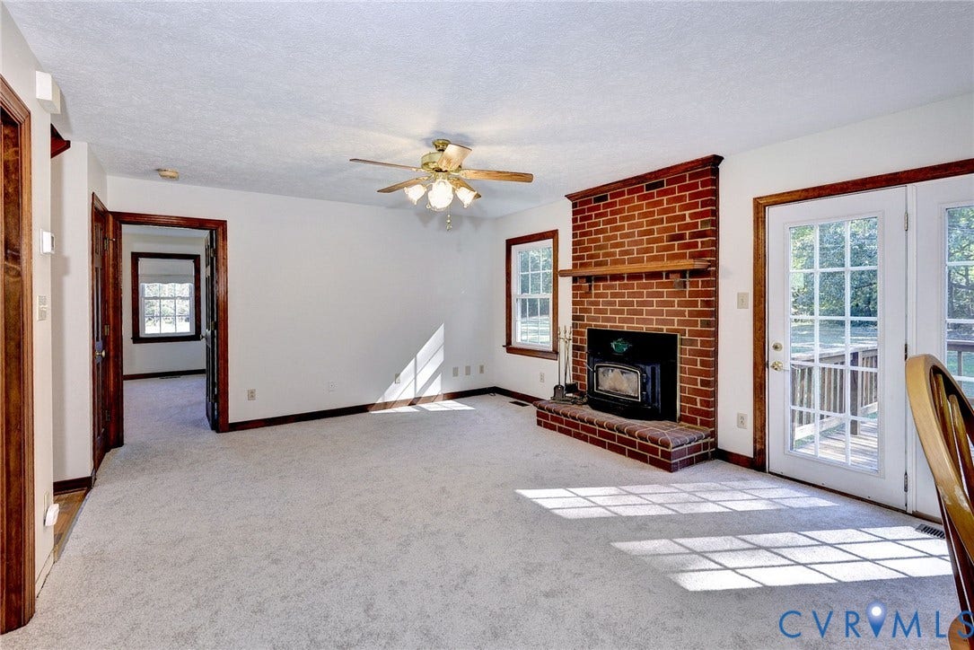 14151 Black Horse Lane, Lanexa, VA 23089 Floor-to-ceiling red brick fireplace with a wood mantle and insert, neutral wall-to-wall carpeting, ceiling fan with light fixture, and double glass-paned doors