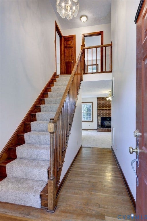 14151 Black Horse Lane, Lanexa, VA 23089 Entryway featuring wood-finish flooring, a staircase with wood railings and carpeted treads, a multi-light flush-mount fixture, and a brick fireplace