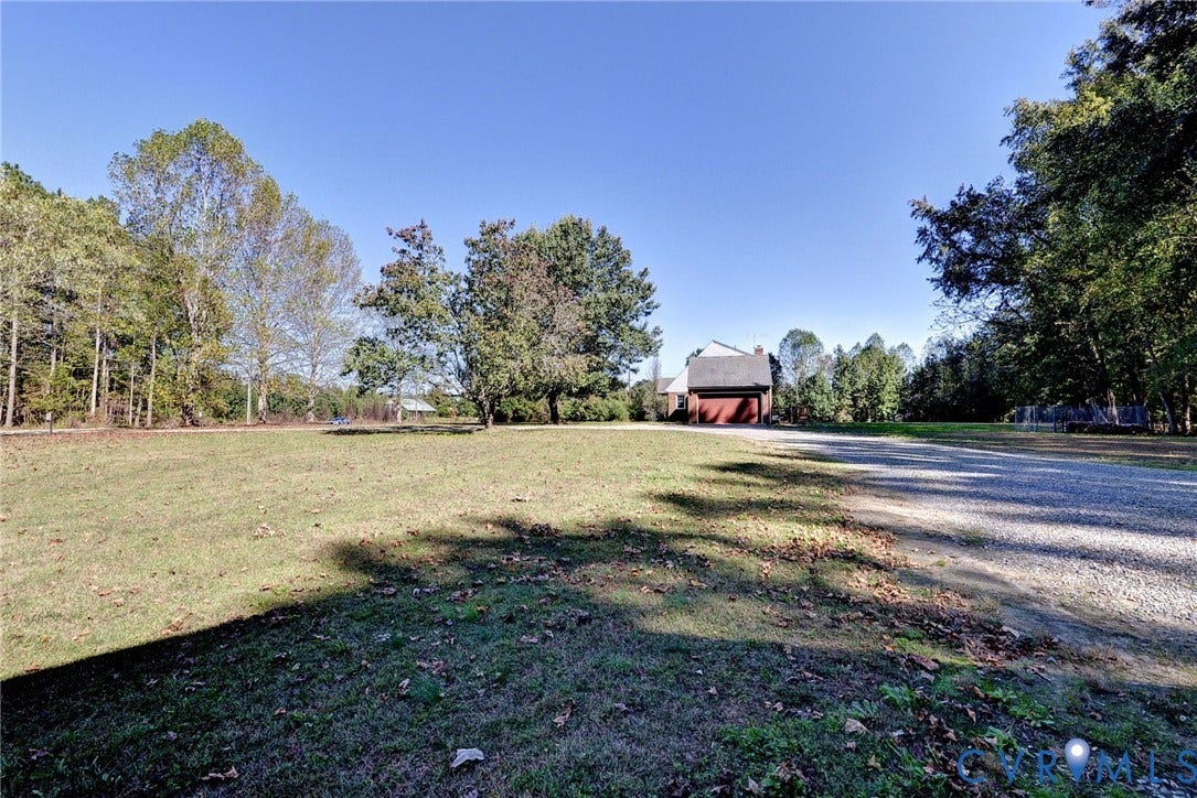 14151 Black Horse Lane, Lanexa, VA 23089 Expansive lot featuring a gravel driveway, mature trees, and a detached structure