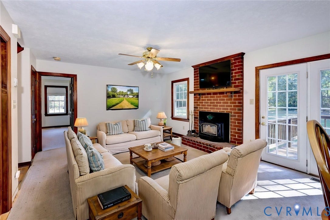 14151 Black Horse Lane, Lanexa, VA 23089 -VIRTUAL STAGING Red brick fireplace with a wood-burning insert and timber mantel, floor-to-ceiling glass-paneled double doors, and wood-finish trim throughout