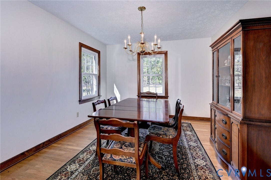 14151 Black Horse Lane, Lanexa, VA 23089 Dining area featuring hardwood flooring, wood-framed windows, a built-in wooden china cabinet, and a multi-arm chandelier