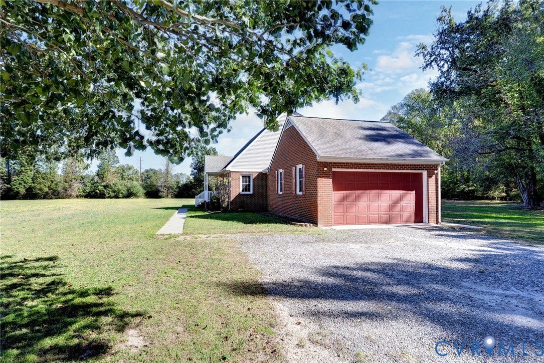 14151 Black Horse Lane, Lanexa, VA 23089 Red brick exterior featuring a multi-car garage, asphalt shingle roofing, and an expansive lawn