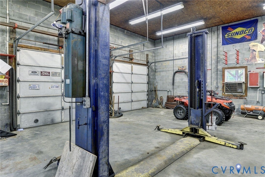 14151 Black Horse Lane, Lanexa, VA 23089 Workshop featuring concrete block walls, concrete flooring, dual metal overhead doors, and a built-in automotive lift