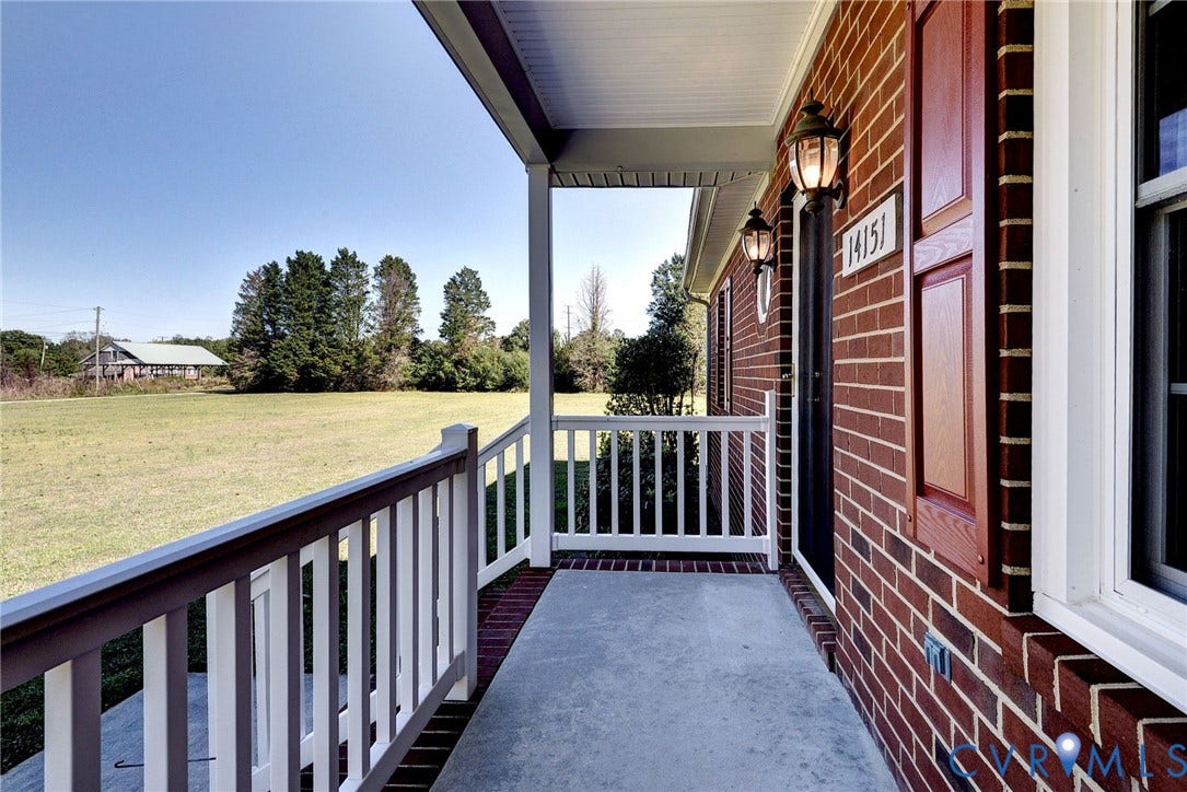 14151 Black Horse Lane, Lanexa, VA 23089 Covered front porch featuring red brick exterior, white railings, decorative shutters, and attached wall-mounted lighting