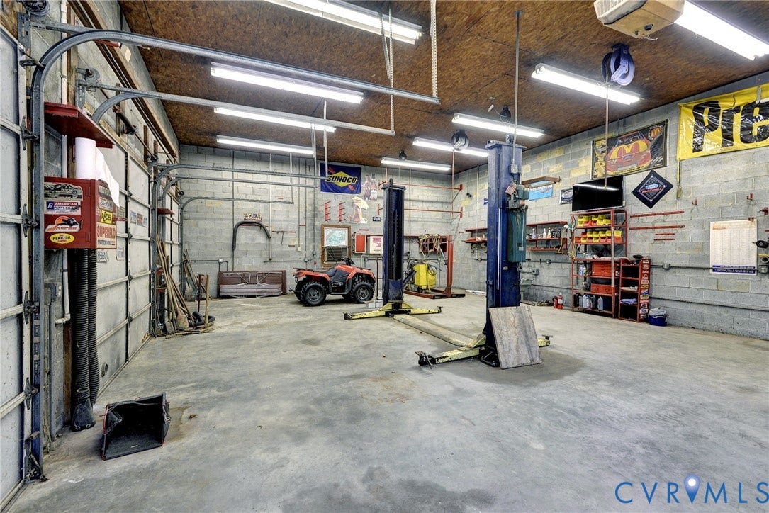 14151 Black Horse Lane, Lanexa, VA 23089 Expansive garage workspace featuring concrete block walls, concrete flooring, high-output overhead lighting, and dual vehicle lifts