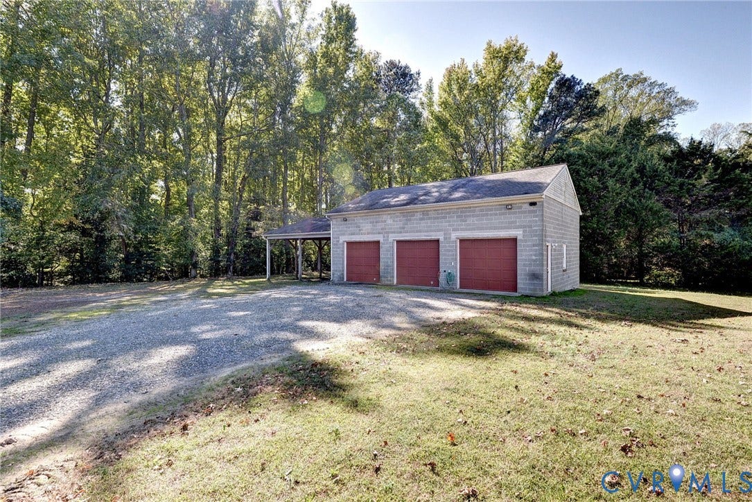 14151 Black Horse Lane, Lanexa, VA 23089 Three-car detached garage featuring masonry exterior, shingle roof, integrated side carport, and gravel driveway
