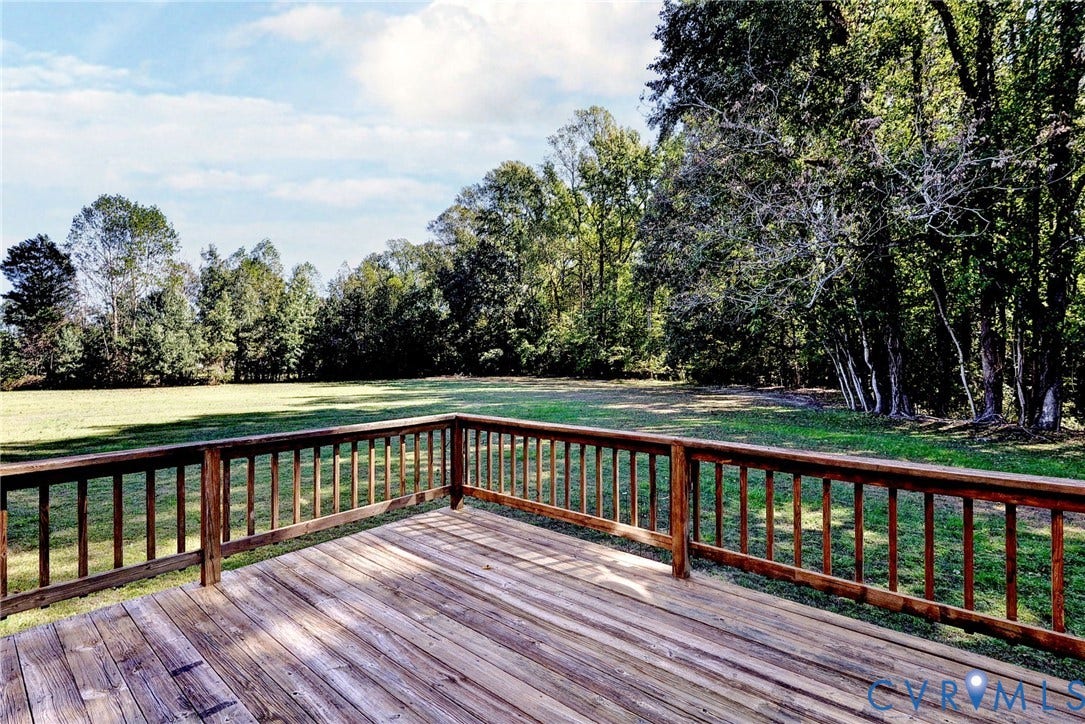 14151 Black Horse Lane, Lanexa, VA 23089 Elevated wooden deck featuring a perimeter railing, overlooking a sprawling grass lawn and a dense tree line