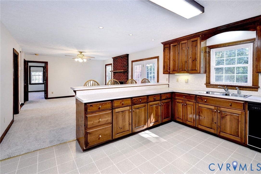 14151 Black Horse Lane, Lanexa, VA 23089 Kitchen featuring wood cabinetry, white countertops, double-basin stainless steel sink, tiled flooring, and a brick fireplace