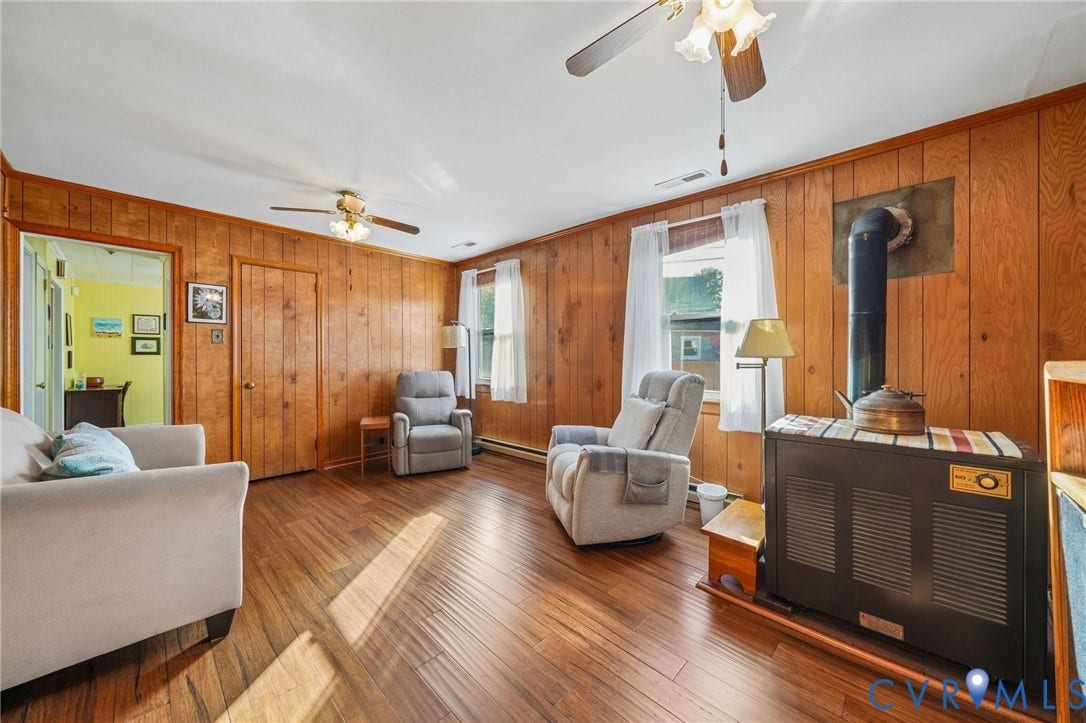 3030 Brentwood Circle, Chesterfield, VA 23237 Wood-panelled interior featuring wood-finish flooring, dual ceiling fans, and a built-in metal wood heating stove
