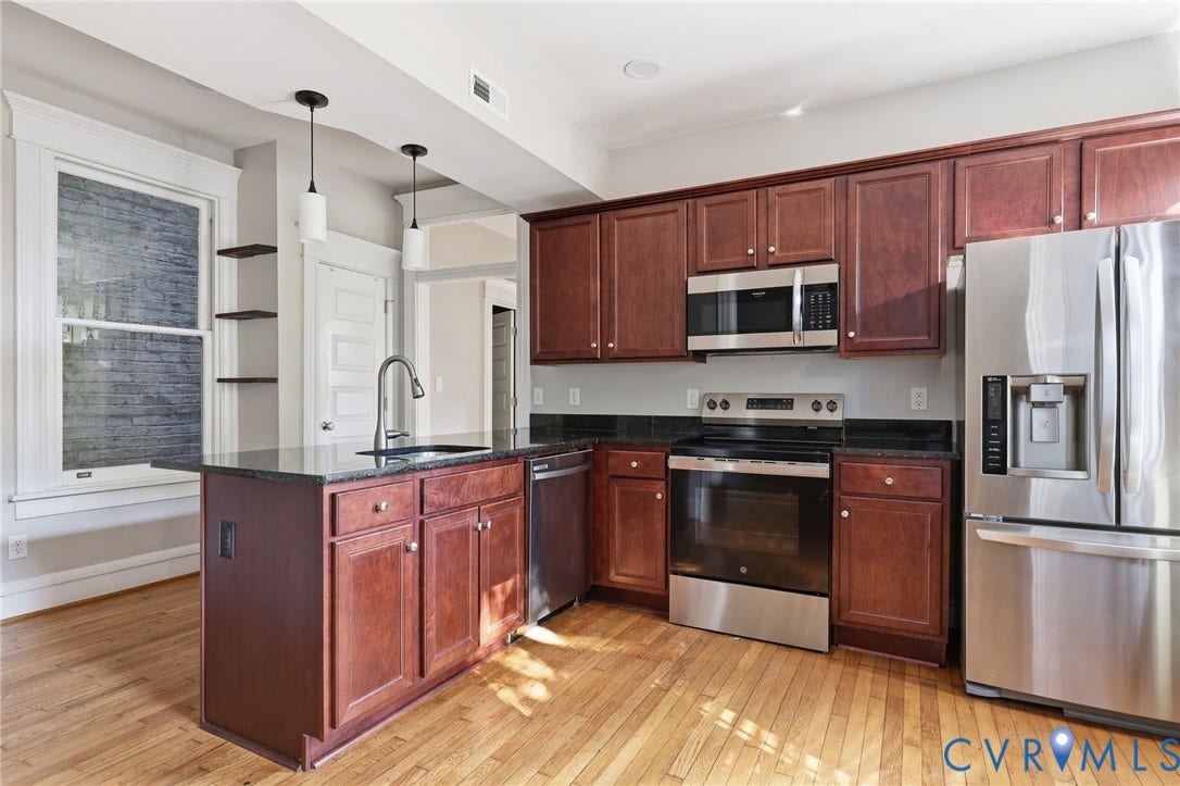 101 N Stafford Avenue, #U4, Stafford Terrace Condo, Richmond, VA 23220 Kitchen featuring stained wood cabinetry, dark stone countertops, stainless steel appliances, wood-finish flooring, and dual pendant lighting over the peninsula
