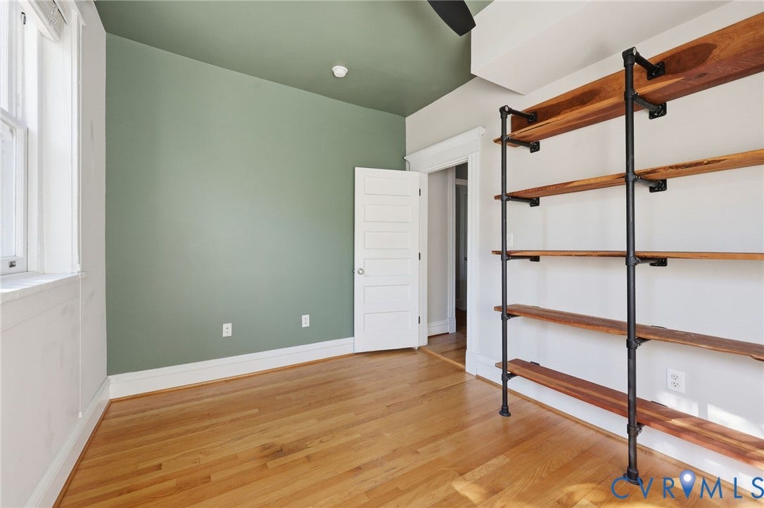 101 N Stafford Avenue, #U4, Stafford Terrace Condo, Richmond, VA 23220 Room featuring wood flooring, industrial-style wall-mounted shelving with metal pipe supports, wood-finish shelves, and a five-panel interior door