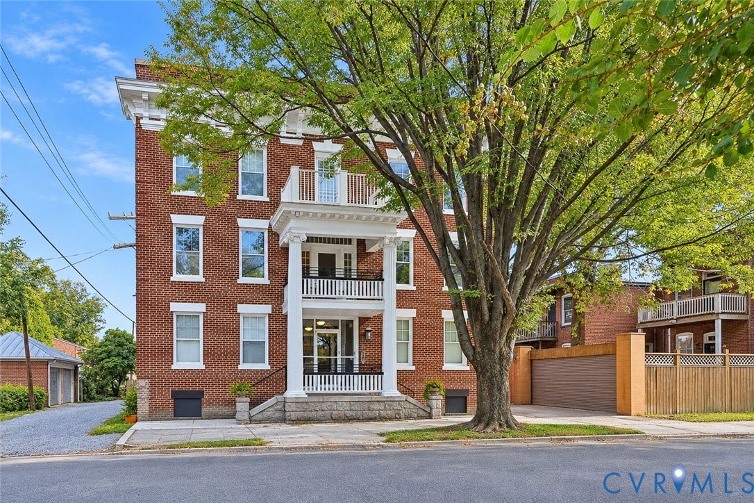 101 N Stafford Avenue, #U4, Stafford Terrace Condo, Richmond, VA 23220 Three-story brick exterior featuring a covered porch with classical columns, stacked balustraded balconies, a stone foundation, and a detached multi-bay garage