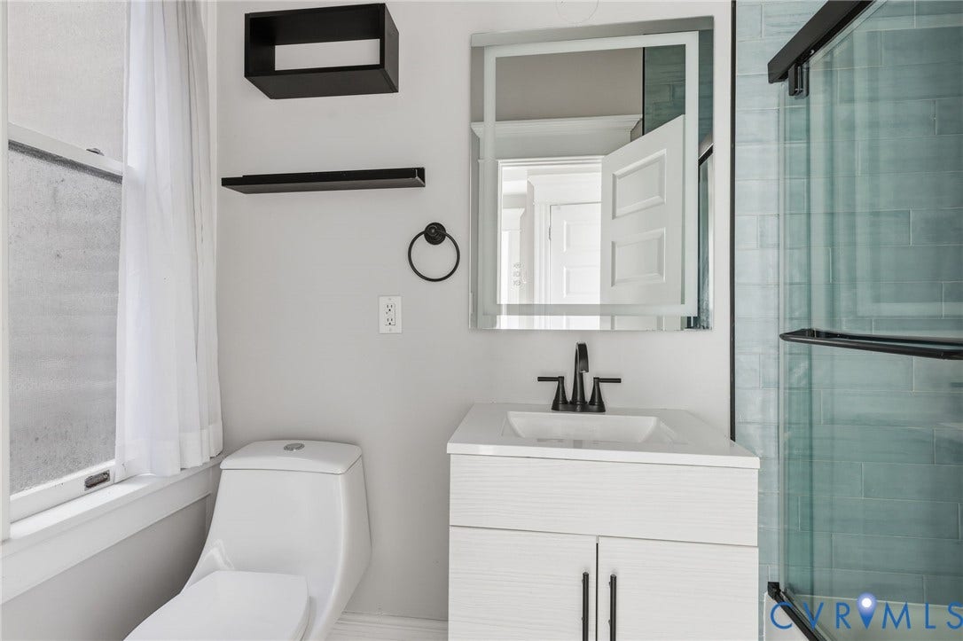 101 N Stafford Avenue, #U4, Stafford Terrace Condo, Richmond, VA 23220 Modern vanity with an integrated sink and matte black faucet, illuminated mirror, glass-enclosed shower featuring subway-style tile, and black wall-mounted shelving