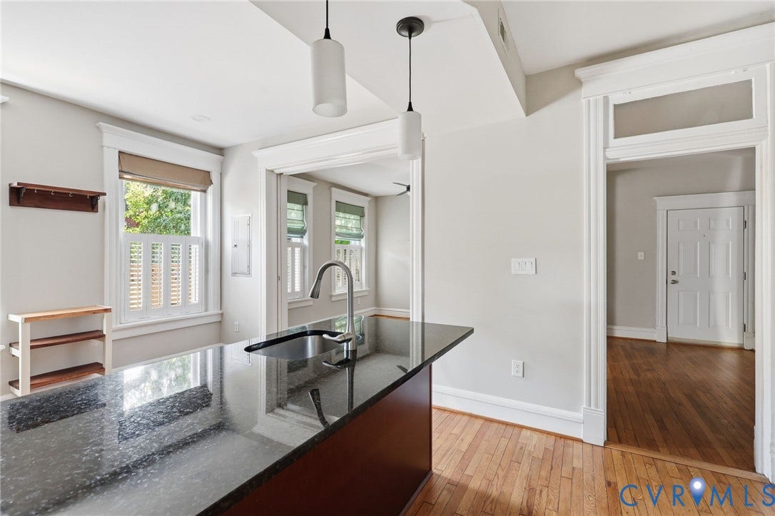101 N Stafford Avenue, #U4, Stafford Terrace Condo, Richmond, VA 23220 Kitchen island featuring a stone countertop, under-mount sink, and dual pendant lighting, complemented by wood-finish flooring, transom-style doorway trim, and traditional window casings
