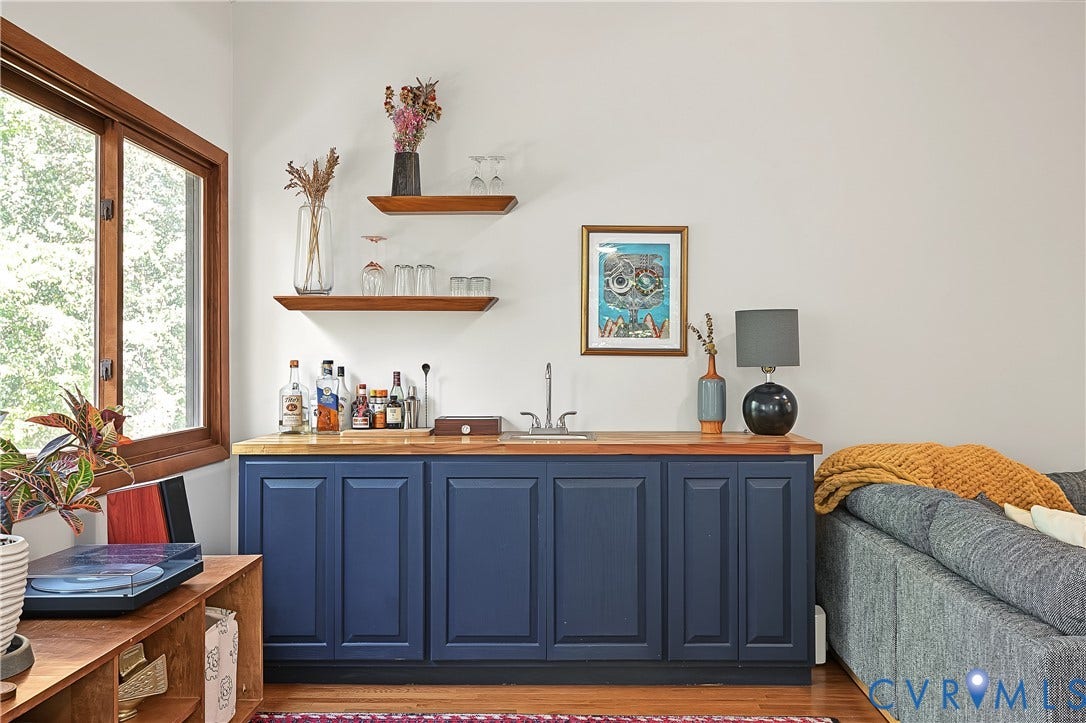 3800 Pheasant Hollow Drive, Henrico, VA 23231 Built-in wet bar featuring navy blue shaker-style cabinetry, wood countertop, stainless steel sink basin, and two natural wood floating shelves
